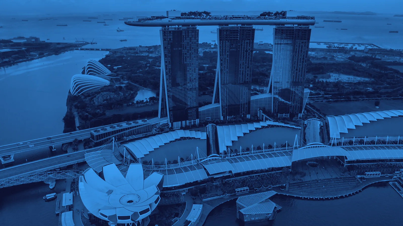Blue-on-ink duotone photograph of the Singapore skyline at dusk, the host city of Interchange Singapore 2026.