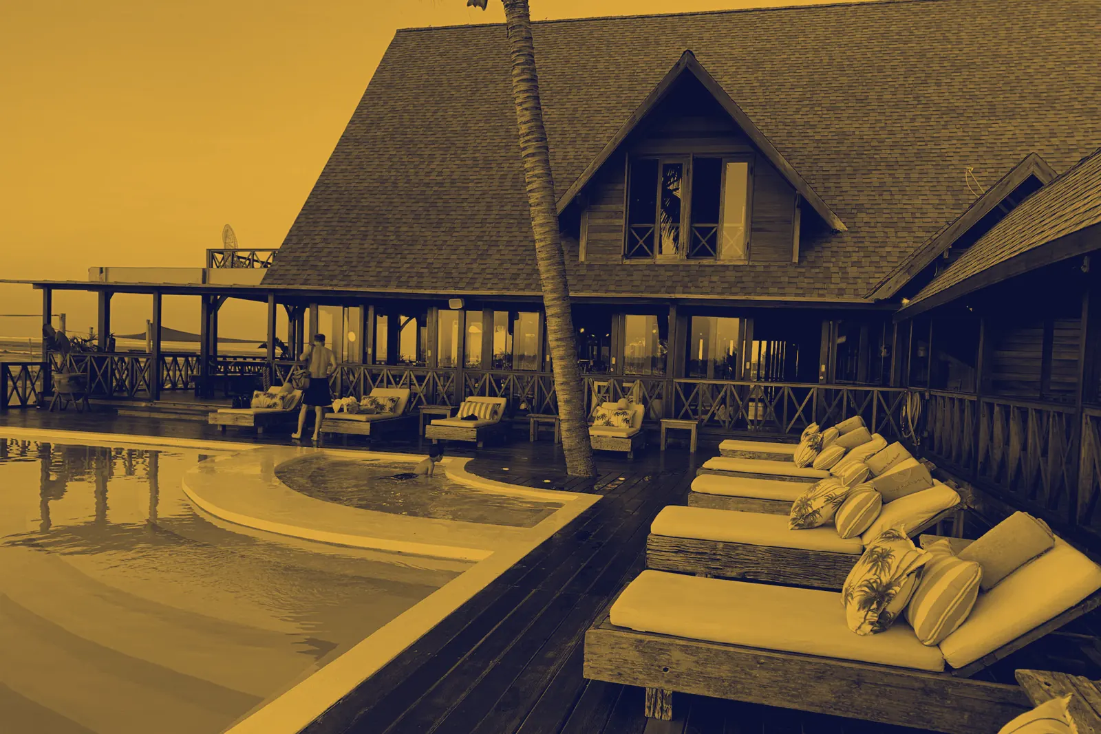 Duotone gold-tinted photograph of a resort terrace overlooking the sea, the kind of high-end itinerary LuxuryEscapeGuide researches.